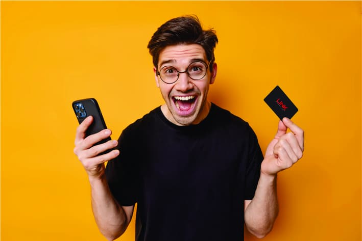 a person smiling with holding link card in one hand and mobile in other hand